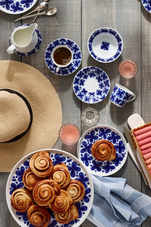 Zweedse kaneelbroodjes zijn het beroemdste fika gebak, zelfs buiten de grenzen van Zweden. Hier zie je ze geserveerd op het Mon Ami servies van Rörstrand op een tafel naast een zomerhoed.