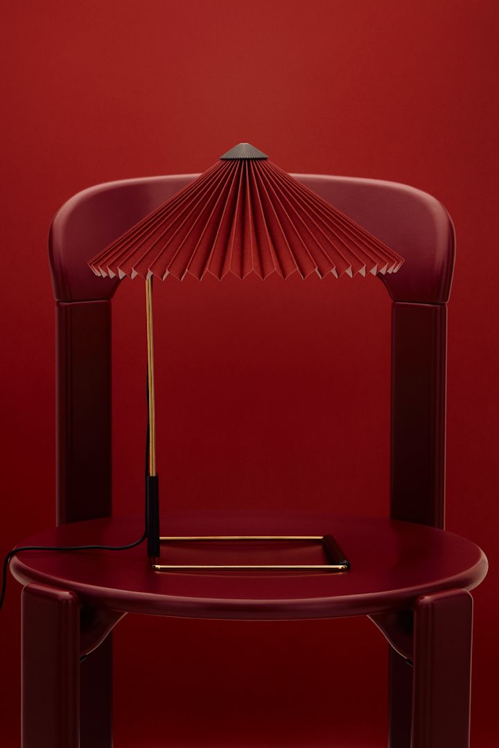 Kersenrood is een van de interieurtrends van 2025. Hier zie je de Matin lamp op een rode stoel tegen een achtergrond in dezelfde kleur.
