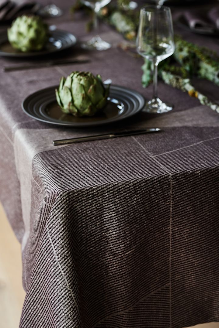 Een bruin tafelkleed van NJRD met het bruine Lines-bord ook van NJRD op een elegante en rustieke tafelsetting.