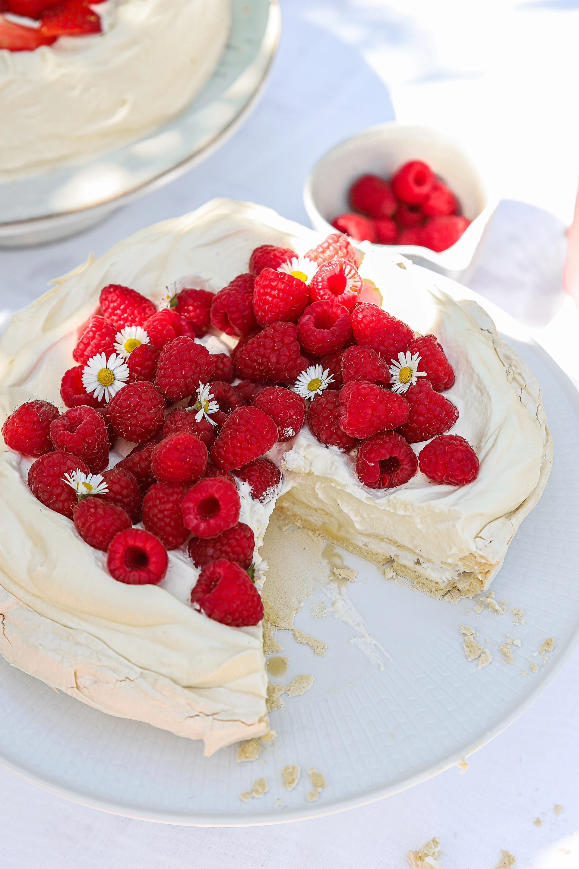 Frida Skattberg “Baka med Frida” bakt eenvoudige taarten voor midzomer, zoals deze knapperige en eenvoudige schuimtaart met room en frambozen, versierd met prachtige bloemen.
