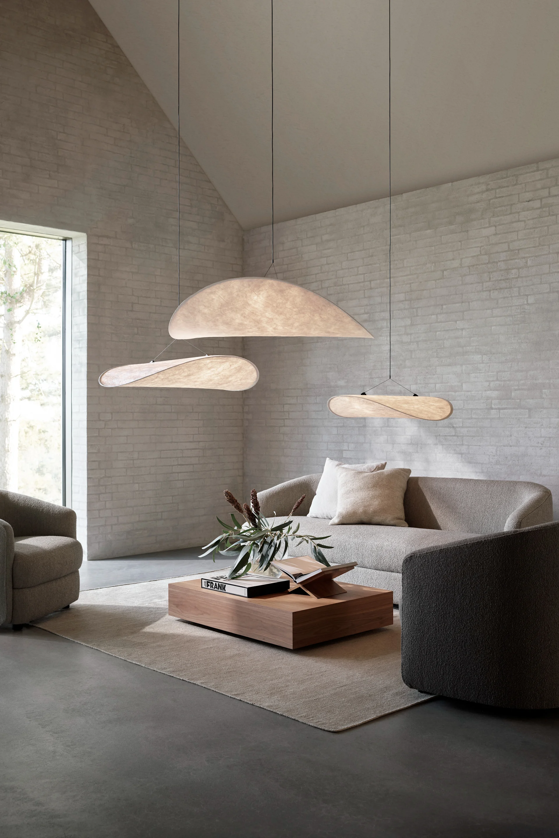 De juiste plafondlamp vinden voor je woonkamer: Hier zie je de Tense hanglamp van New Works in verschillende maten hangen in een woonkamer met een hoog plafond.