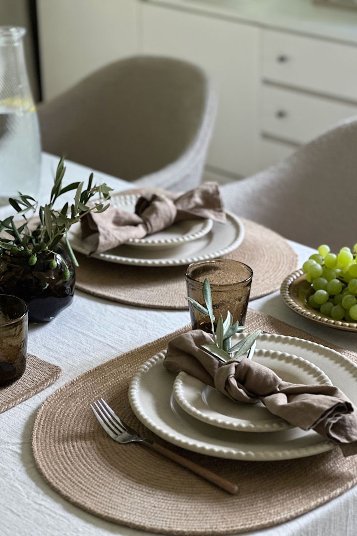 Een warme, aardse tafelschikking met Daria borden in de kleur zand van Pottery Jo samen met een linnen tafelkleed en jute placemats.