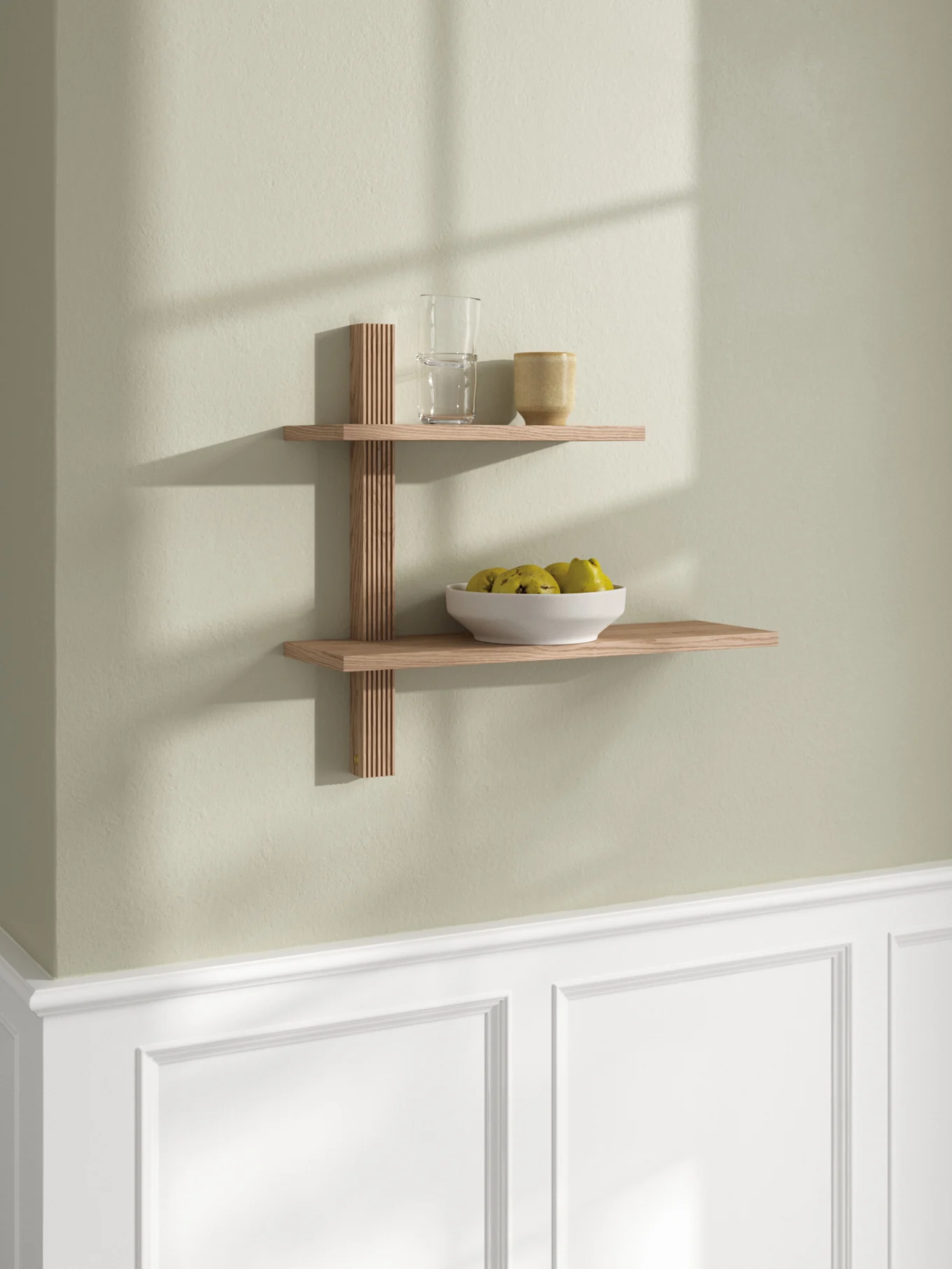 Tweelaags houten wandplank met lattensteun, met een glas, een mok en een kom met geelgroen fruit.