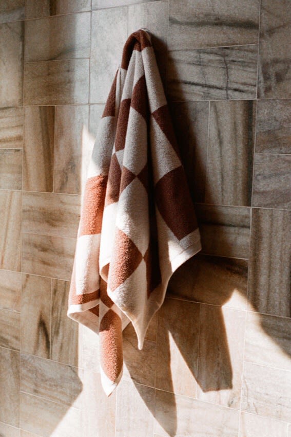 Pantone heeft Mocha Mousse uitgeroepen tot de kleur van het jaar 2025, hier zie je een geruite handdoek van HAY in deze bruintint aan de muur hangen.