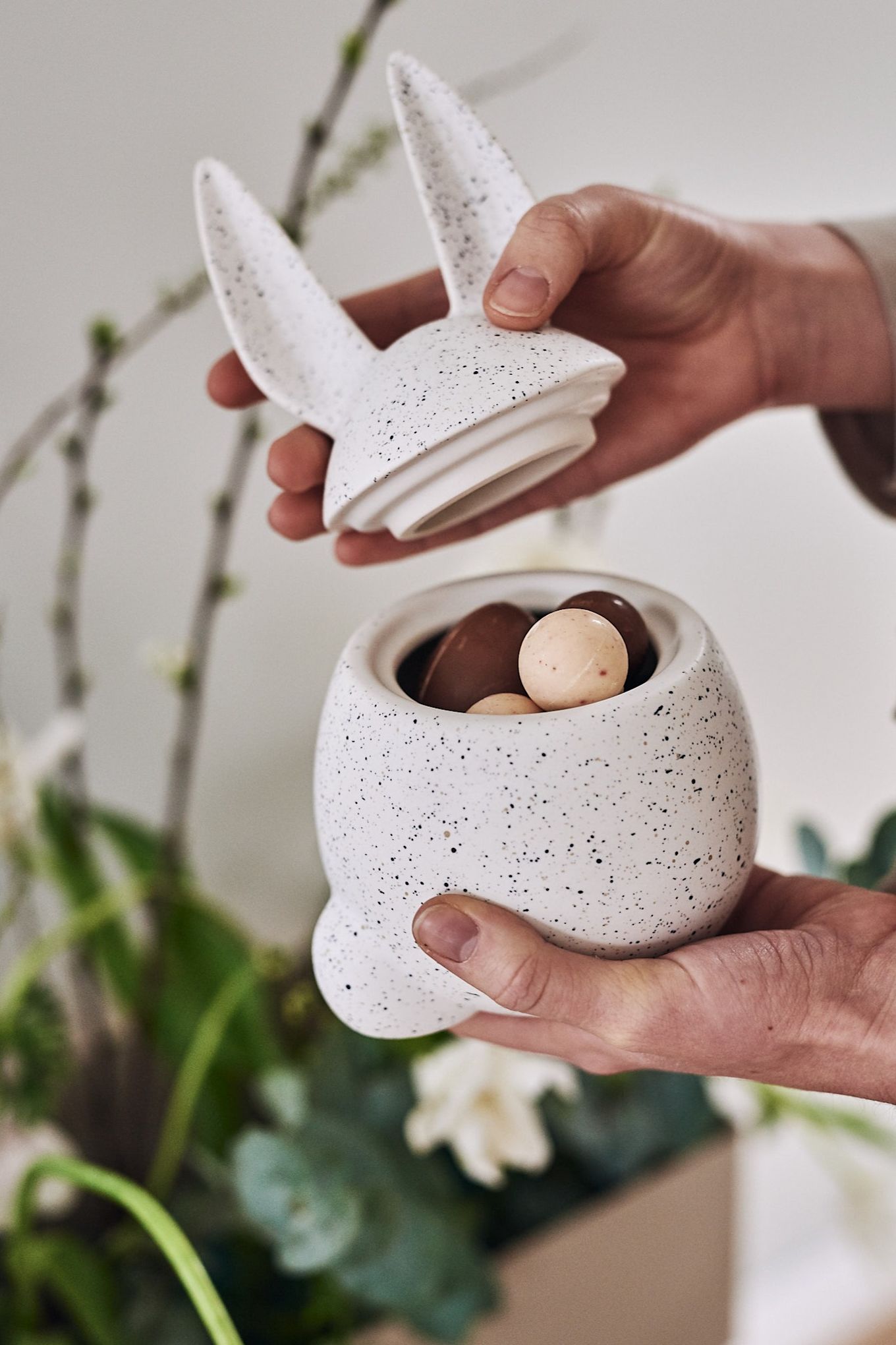 Witte, gespikkelde pot van DBKD in de vorm van een konijn, gevuld met paassnoepjes. 