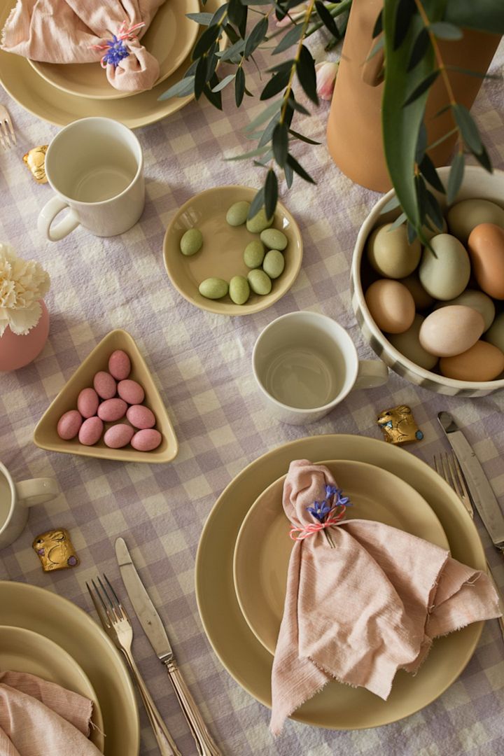 Een goed idee voor de paastafel is altijd een mooi gevouwen servet, zoals je hier ziet met een eenvoudige scrunch en bloem gewikkeld rond een Scandi Living linnen servet in roze. 