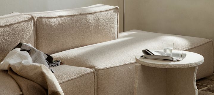 Beige woonkamer met bank, salontafel en knusse plaids van Ferm Living.