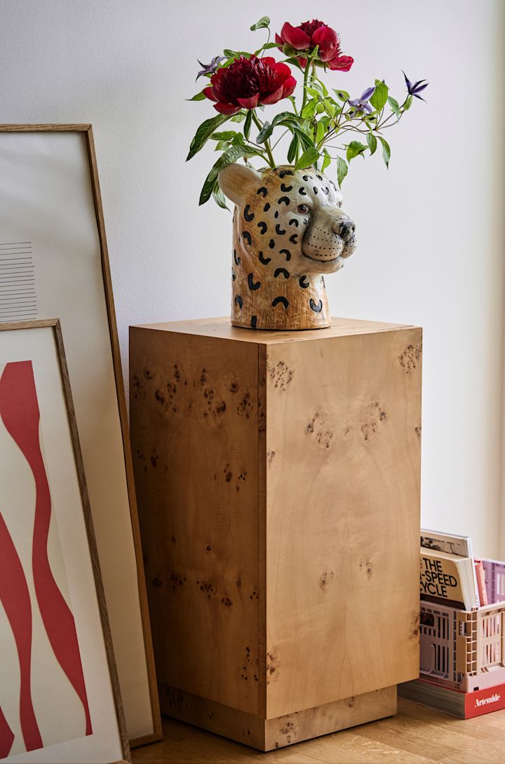 Een van Byons bestsellers en meest iconische producten is de Cheetah-vaas, de cheetah-vaas die verkrijgbaar is in twee verschillende maten. Hier staat hij op een voetstuk met een boeket erin.
