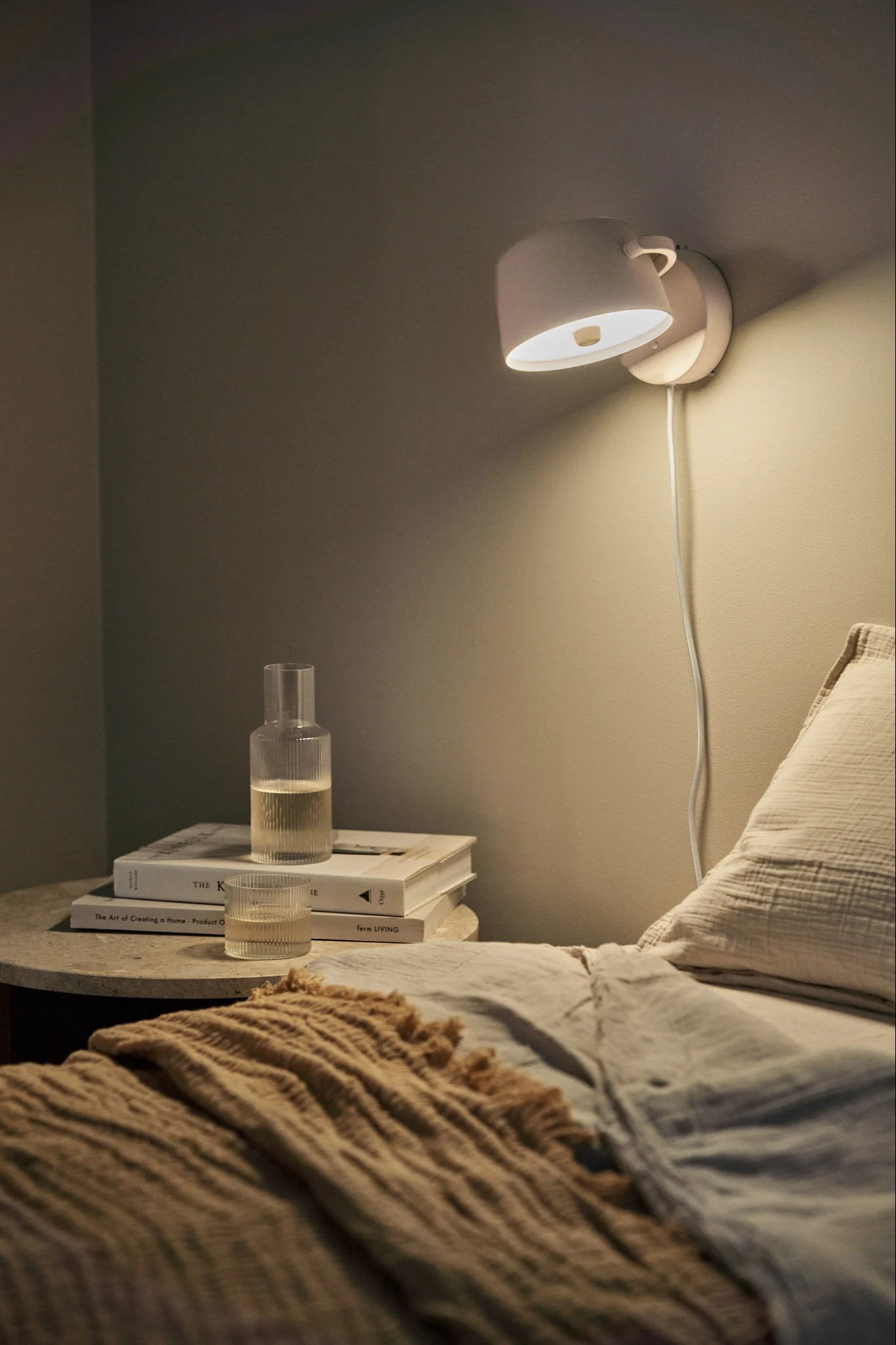 Verlevendig je huis met moderne wandverlichting - hier zie je de Halo wandlamp van Scandi Living in beige aan de muur boven een bed. 