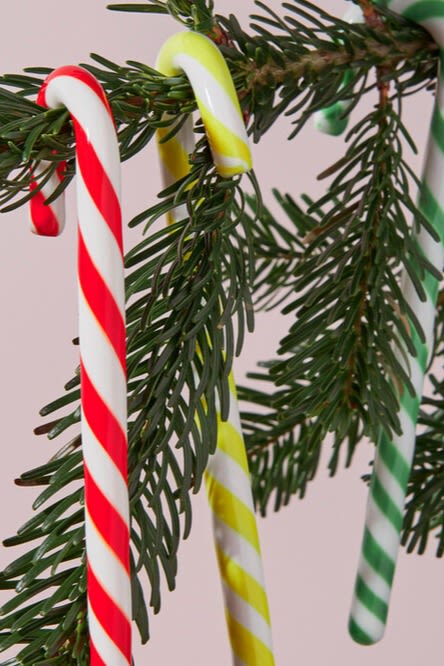 Een hand plaatst een grote ingepakte decoratie snoepje in een kerstboom, een speels en kleurrijk kerstboomdecoratie-idee. 