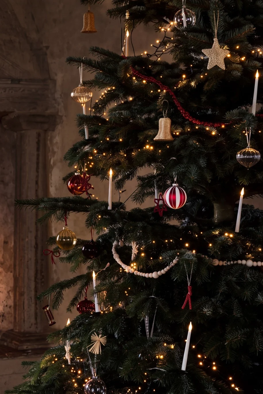 Een versierde kerstboom met lichtjes en ballen naast een gezellige open haard met brandend vuur.