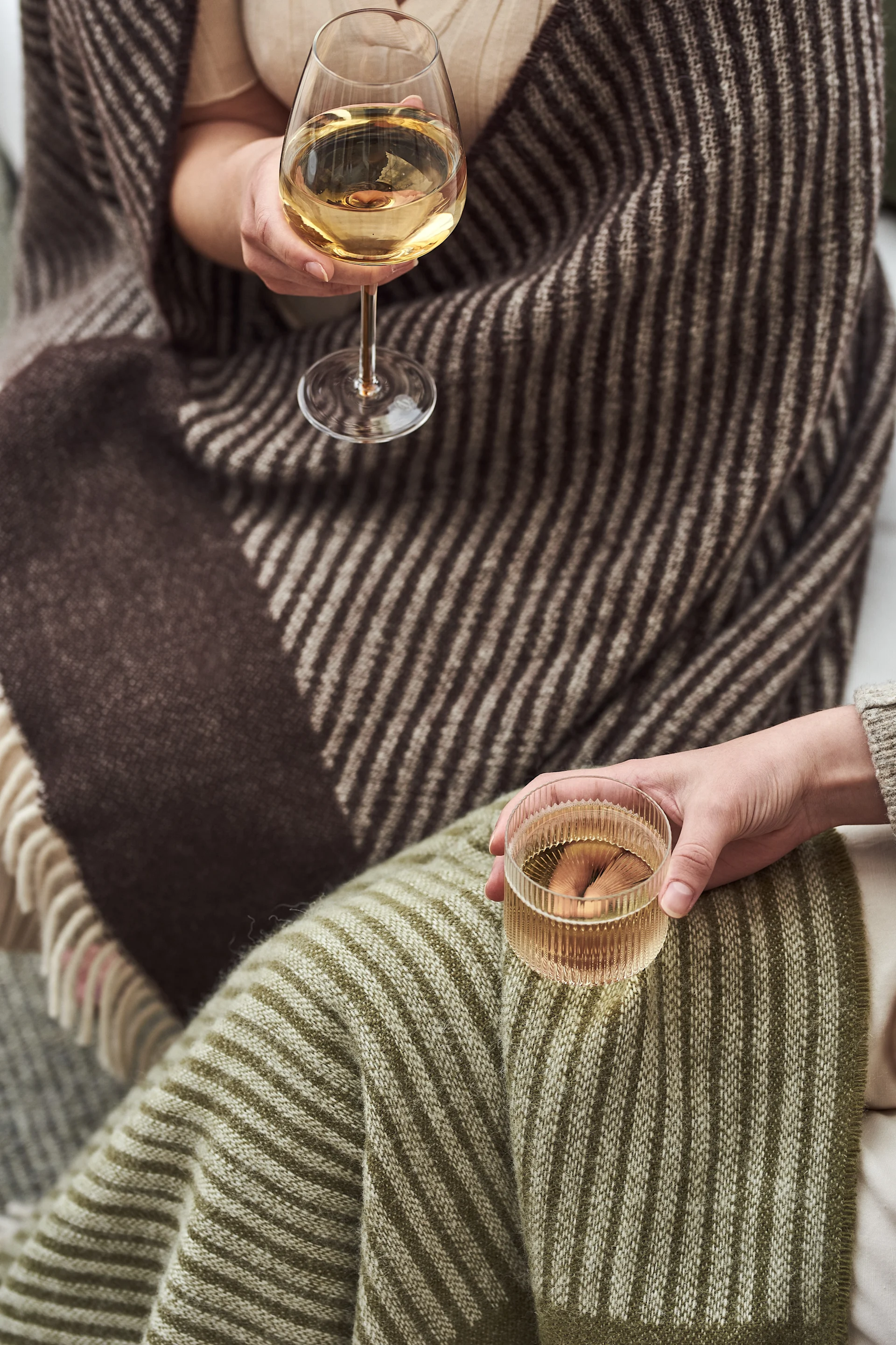 Ripple glazen van Ferm Living, Amber witte vleugel glazen van Broste Copenhagen en Stripes wollen kleden in groen en bruin van NJRD zijn perfect om het balkon te versieren.