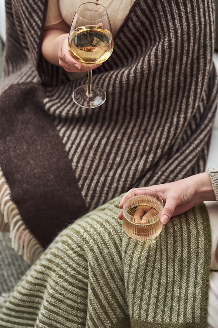 Ripple glazen van Ferm Living, Amber witte vleugel glazen van Broste Copenhagen en Stripes wollen kleden in groen en bruin van NJRD zijn perfect om het balkon te versieren.