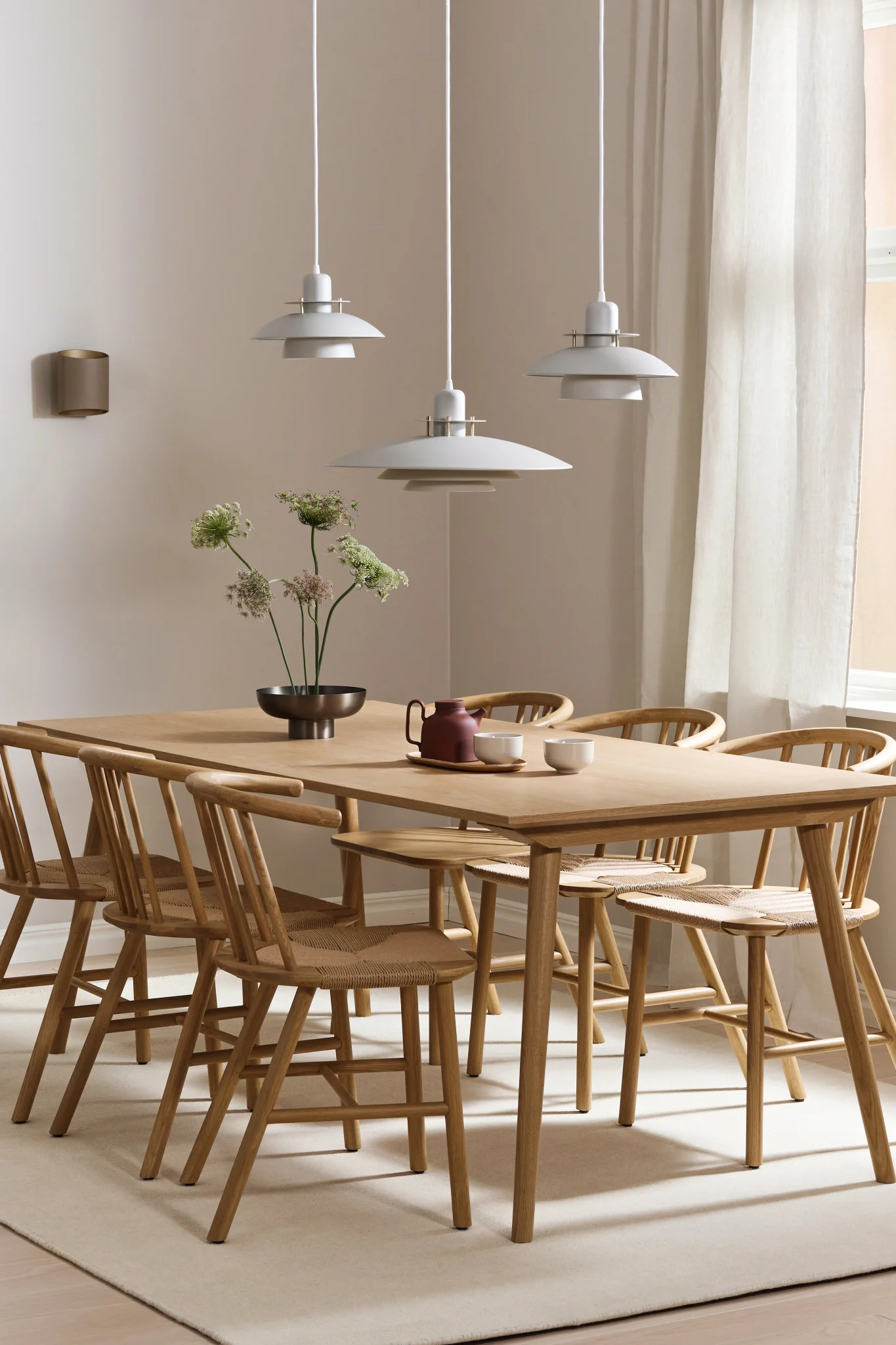 De Primus lamp hangt in een rij van drie en de Sinne lamp aan de muur in een eetkamer.