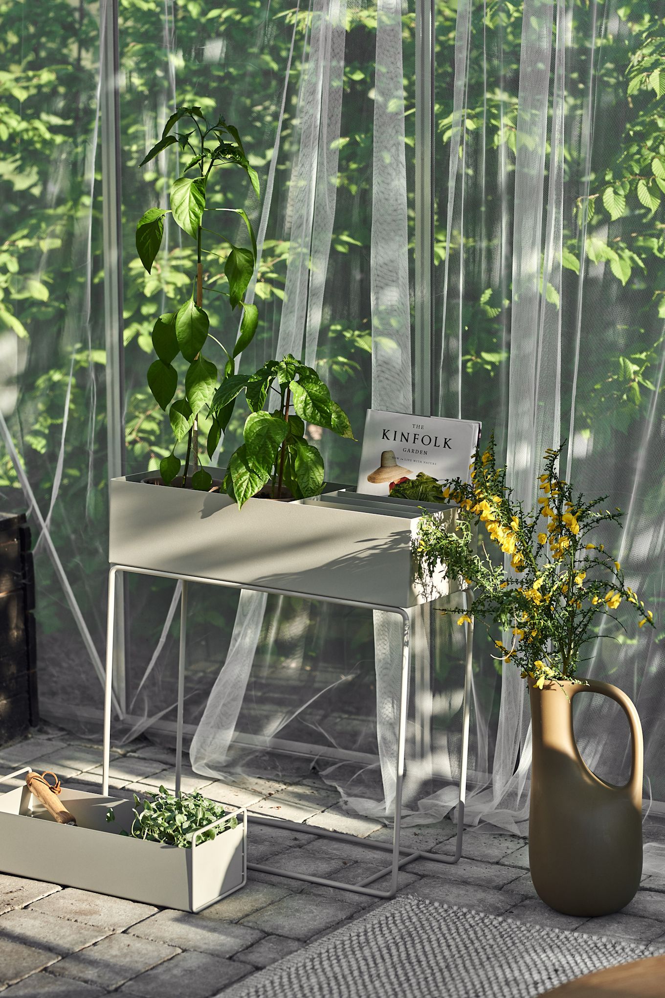 Een gezellig terras, gedrapeerd met stof en verschillende plantenbakken van Ferm Living.
