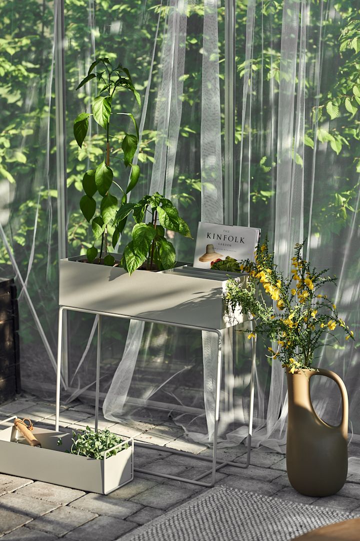 Een gezellig terras, gedrapeerd met stof en verschillende plantenbakken van Ferm Living.