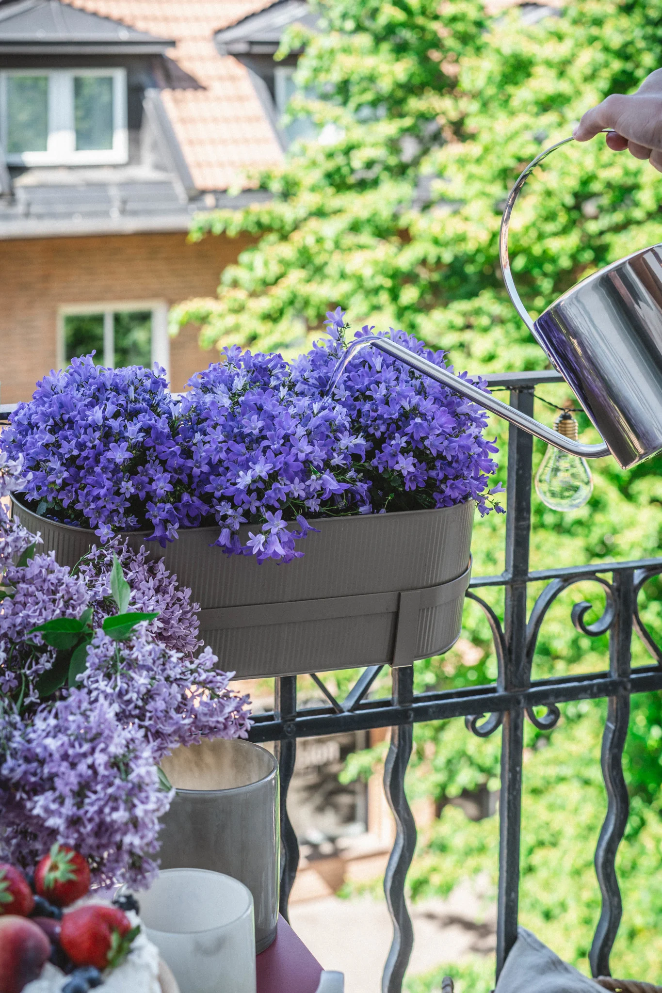 Hier zie je de Bau bloempot in beige van Ferm Living op een balkonreling.