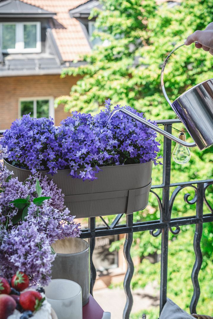 Hier zie je de Bau bloempot in beige van Ferm Living op een balkonreling.
