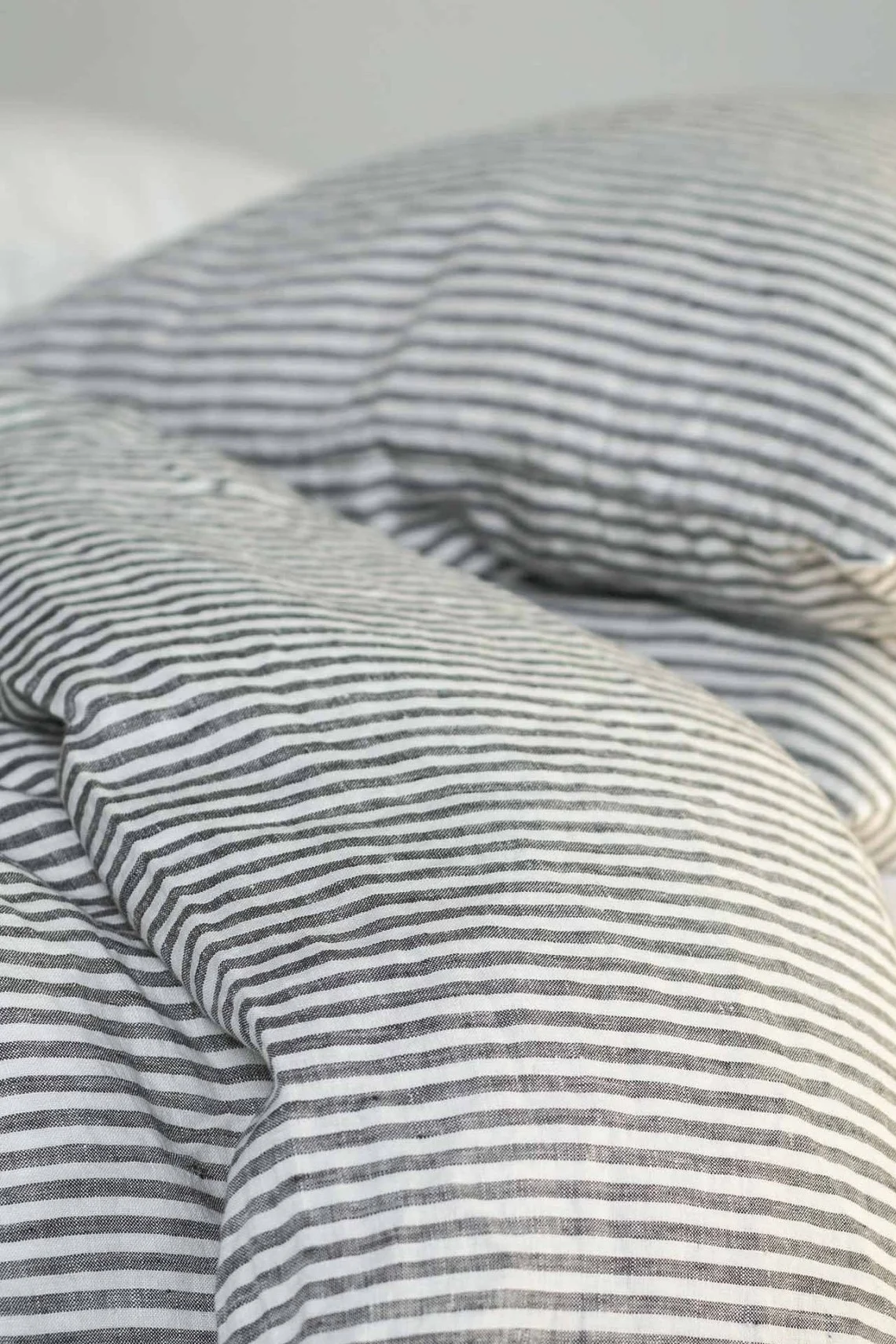 Close-up van een rommelig bed met zwart-wit gestreept linnen beddengoed.