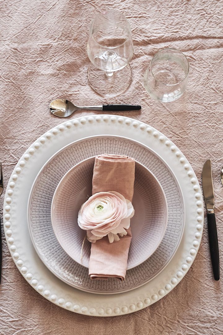 Roze servies is perfect voor een romantische diner thuis, bijvoorbeeld het roze servies uit de Zweedse Grace-collectie van Rörstrand, hier versierd met een bloem.