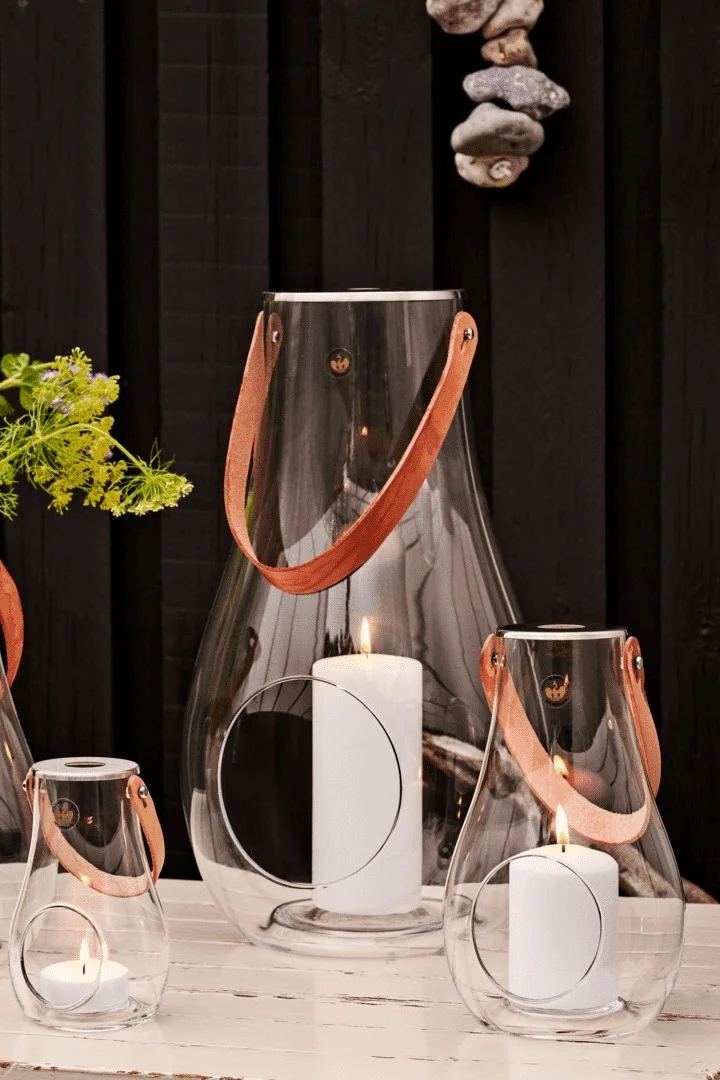 Lantaarns en windlichten kan men het beste in groepen plaatsen. Hier zie je de Design with Lights lantaarn van Holmegaard in verschillende maten.