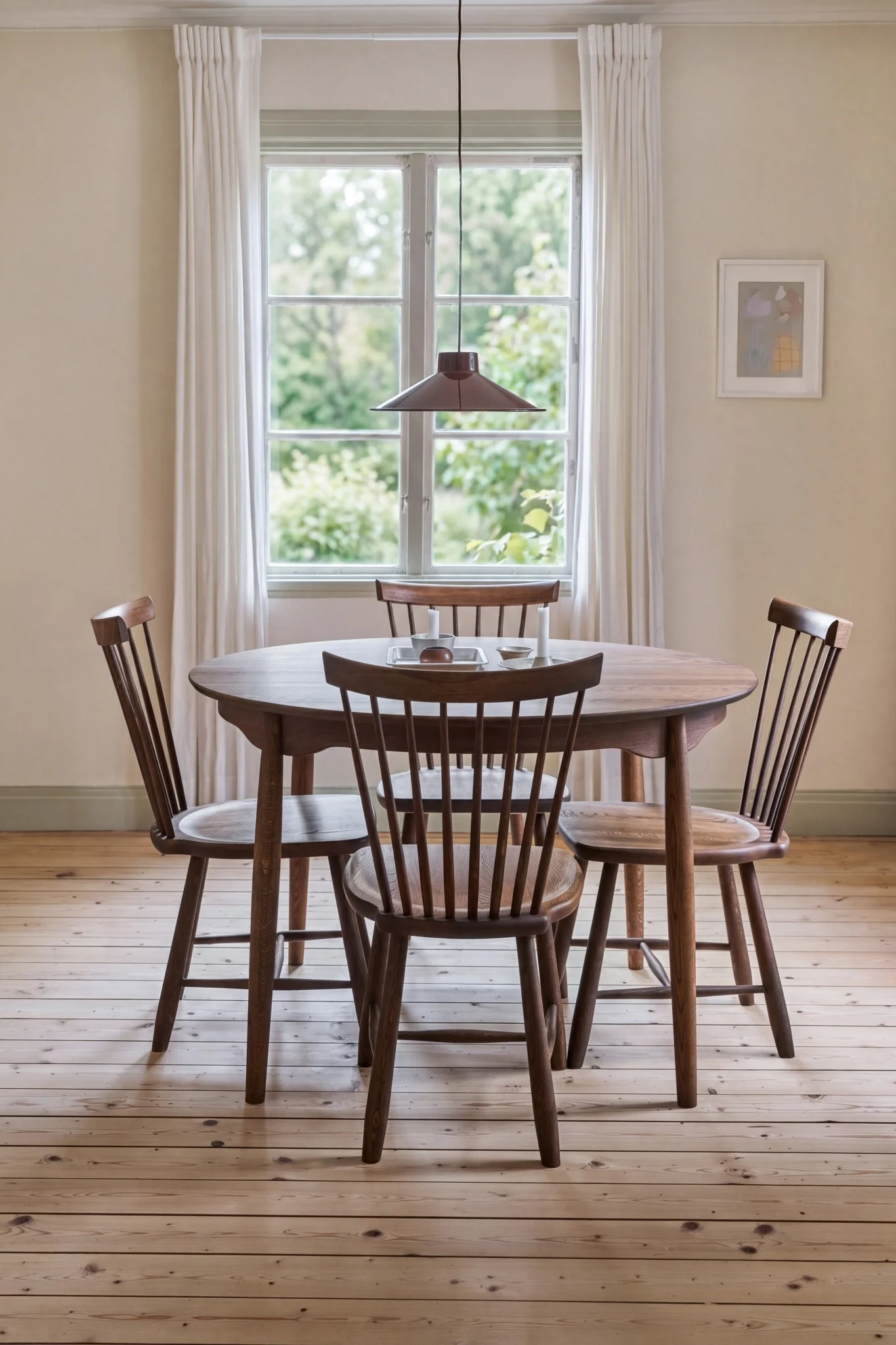 Een gezellige eetkamer met een ronde houten tafel, vier houten stoelen, een raam met witte gordijnen en een hanglamp.