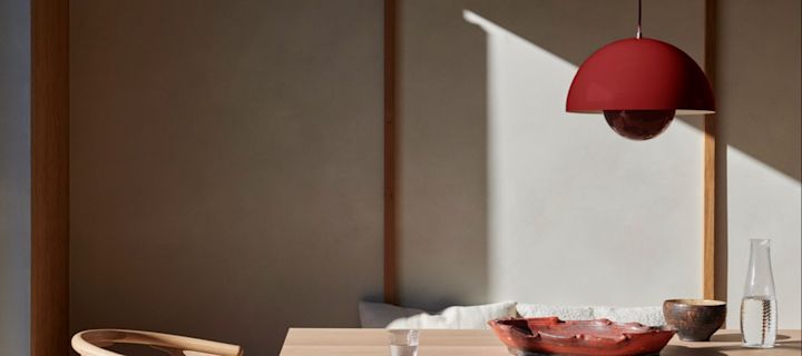 Verlevendig je huis met moderne verlichting - hier zie je de VP1 hanglamp van &Tradition hangen boven een eettafel in een levendige rode kleur. 