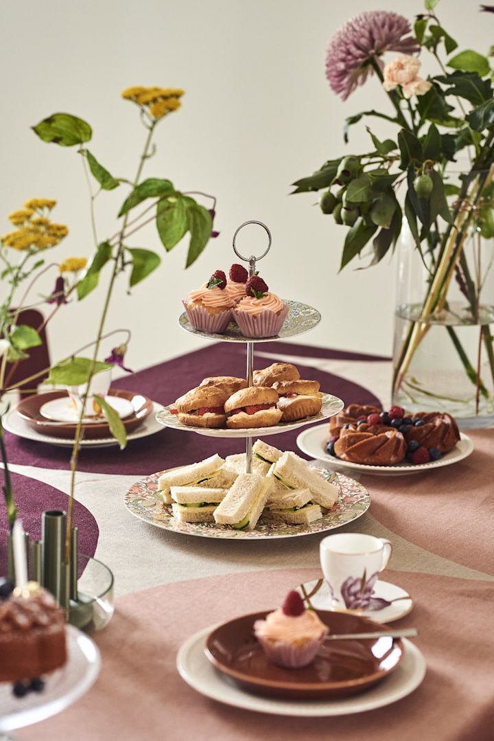 Hier zie je een prachtig gedekte tafel met een etagère met muffins en broodjes.
