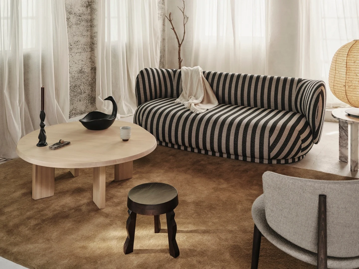 Gezellige woonkamer met een zwart-wit gestreepte bank, lichte houten salontafel en rustiek houten balkenplafond.