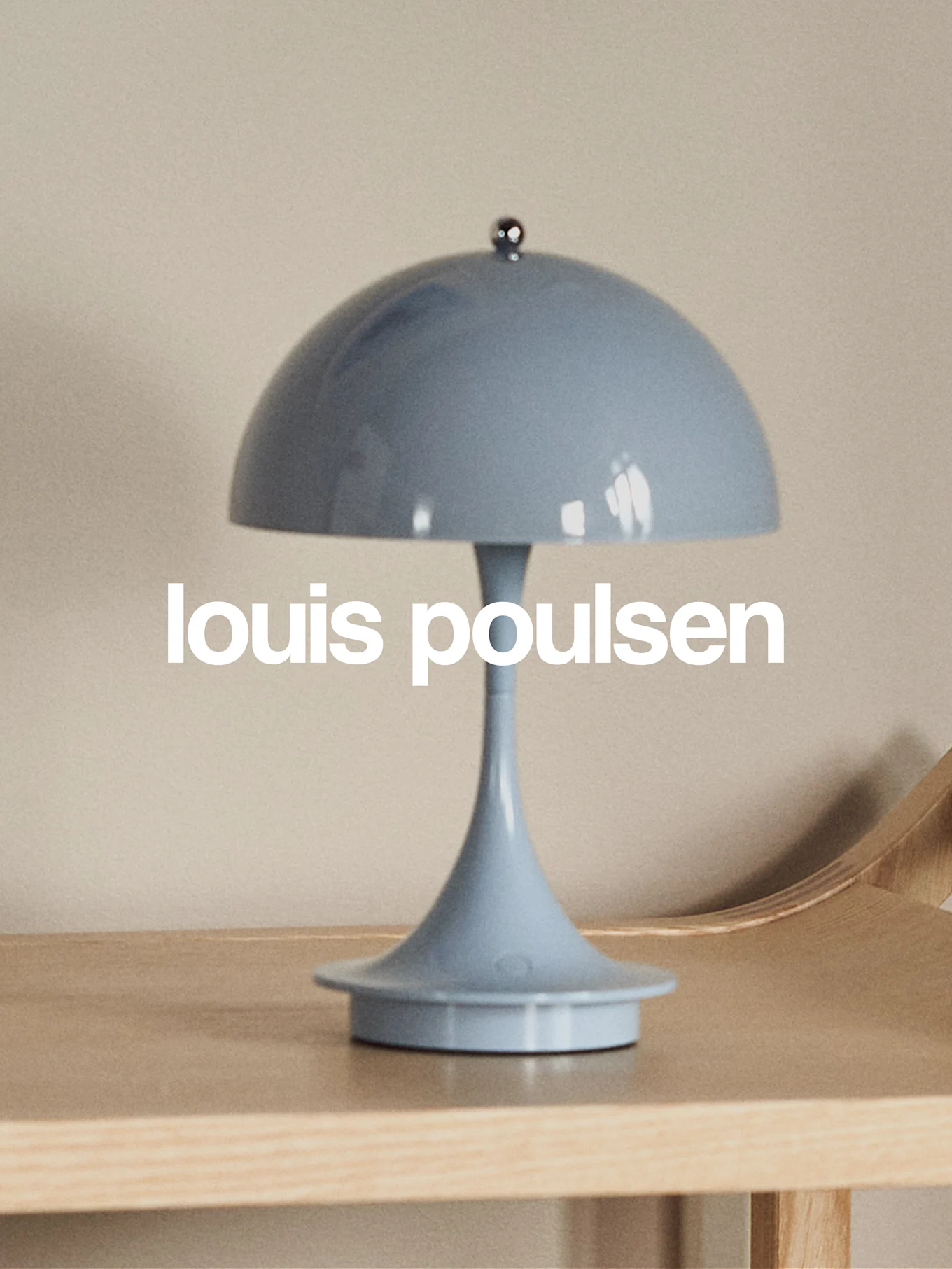 Lichtblauwe paddestoelvormige tafellamp op een houten oppervlak met de tekst 'louis poulsen'.