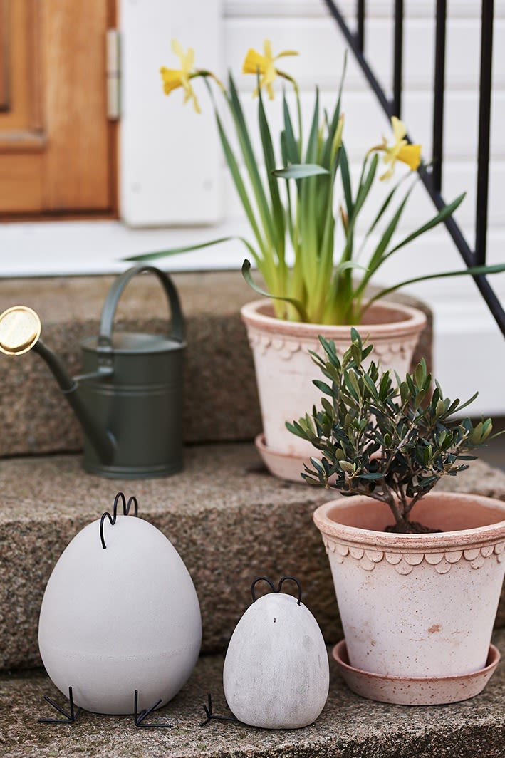 Betonnen paaskippen van DBKD staan op de trap met groene planten in potten van Bergs Potter. 