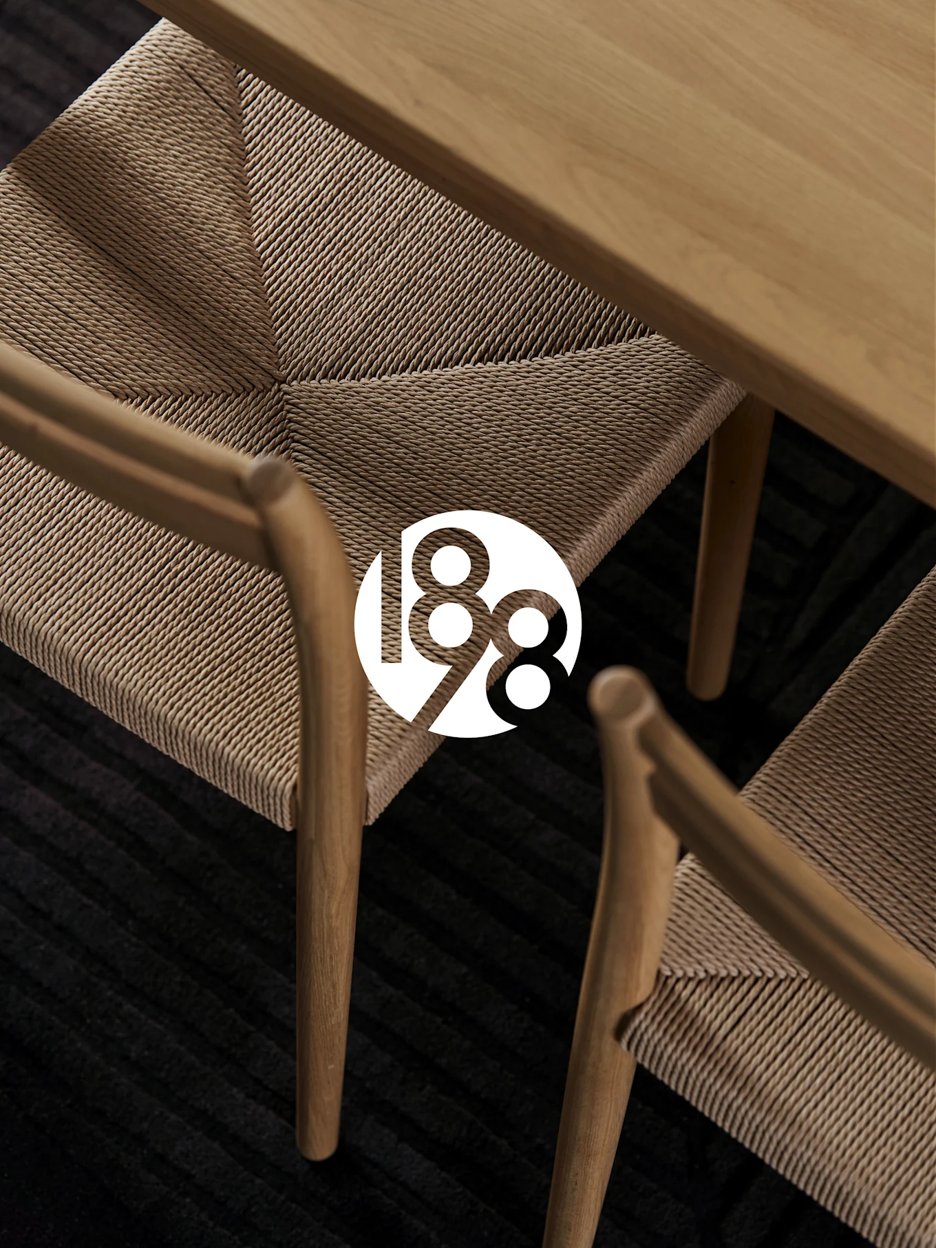 Twee houten stoelen met geweven zittingen, een houten tafel en een donker tapijt. Wit '188' logo overlay.