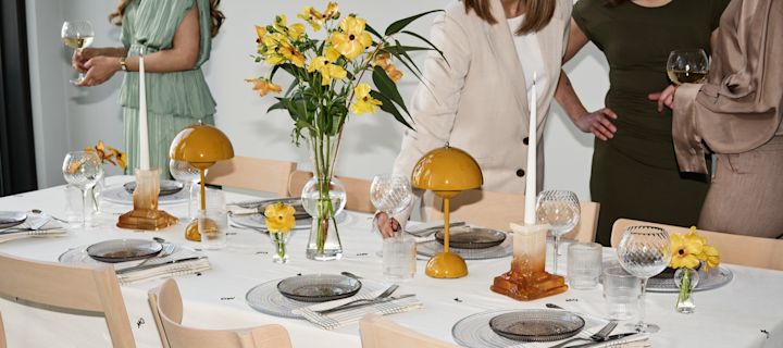 Creëer een feestelijke sfeer: Hier zie je een gedekte tafel met gele accenten en gasten rondom.