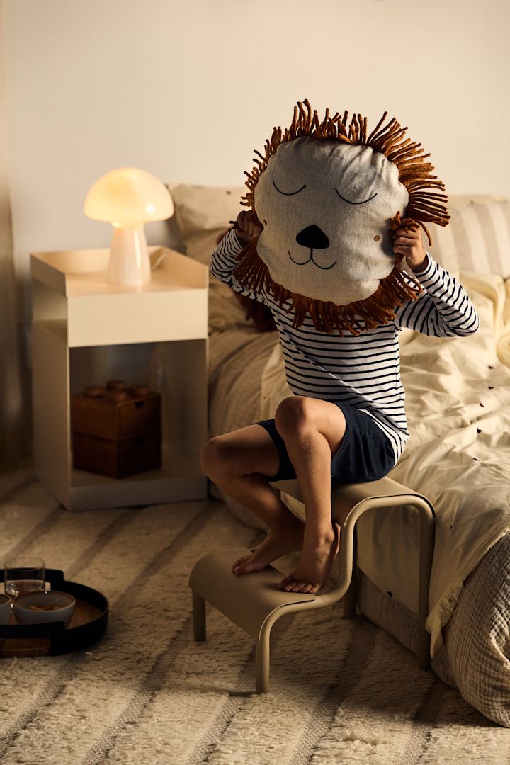 Een kind houdt het leeuwenkussen van ferm living voor zijn gezicht. Met kussens en details kan het kind persoonlijkheid in zijn kamer brengen, een geweldig idee voor elke kinderkamer. 