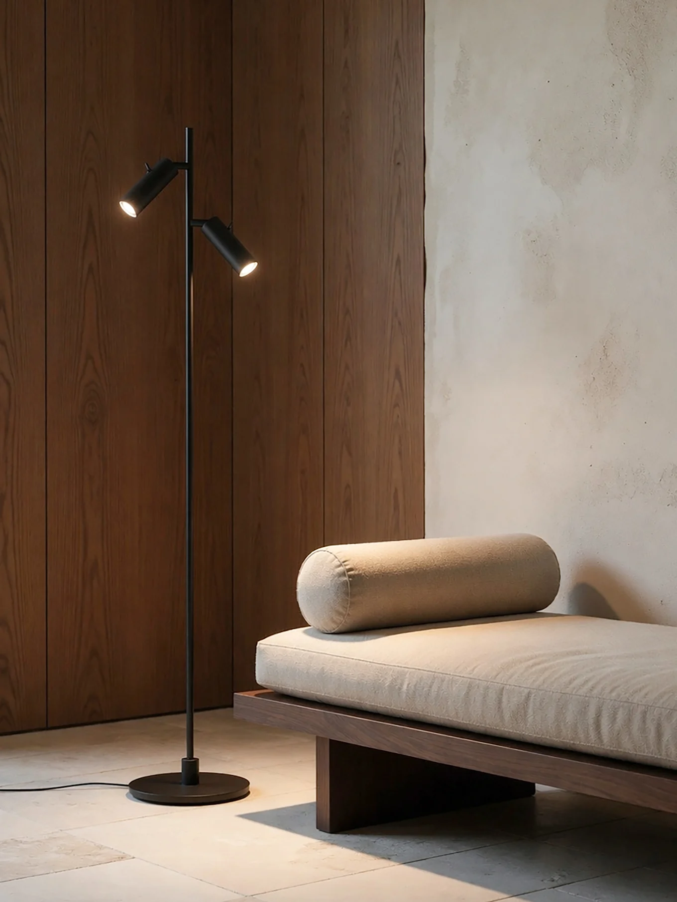 Een moderne kamer met een zwarte vloerlamp met twee lampen naast een houten daybed met een lichtbeige kussen en rolkussen.