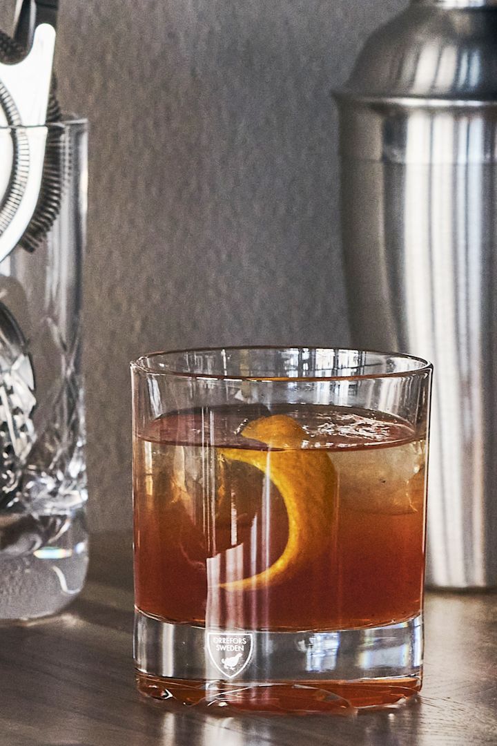 Verschillende soorten cocktailglazen: Welk glas voor welke cocktail? Hier zie je de Carat Old Fashioned drinkglazen van Orrefors met een drankje met ijs en een sinaasappel schijfje erin.