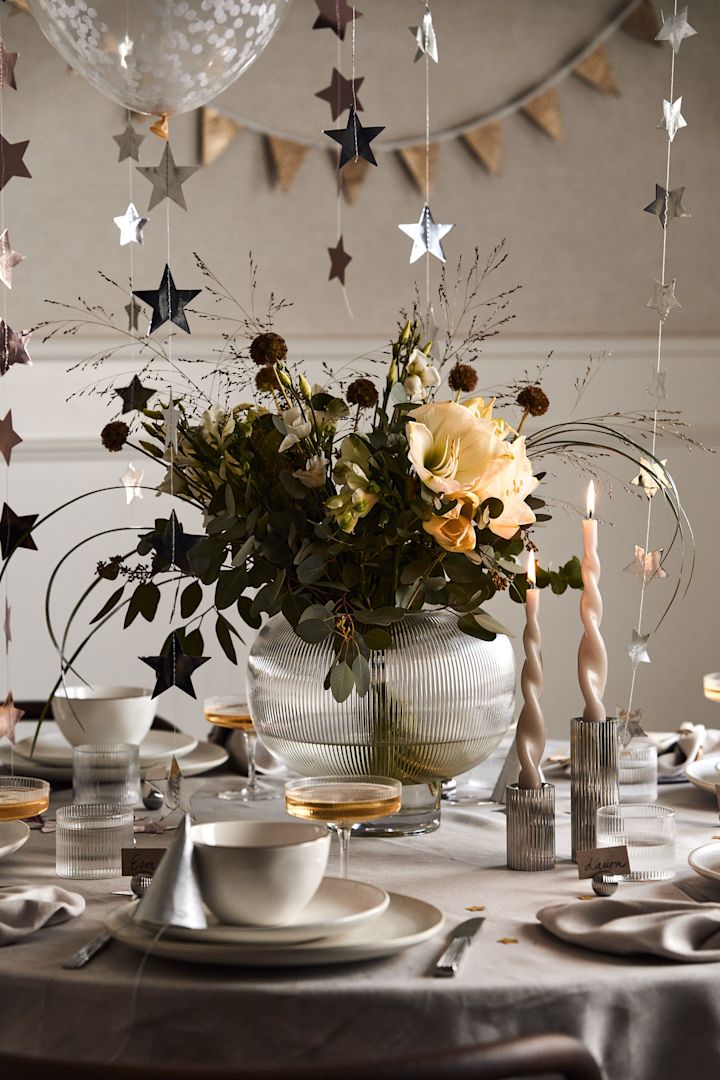 Ideeën voor je nieuwjaarsfeest: Zet een grote vaas met een boeket bloemen erin in het midden van de tafel als blikvanger.
